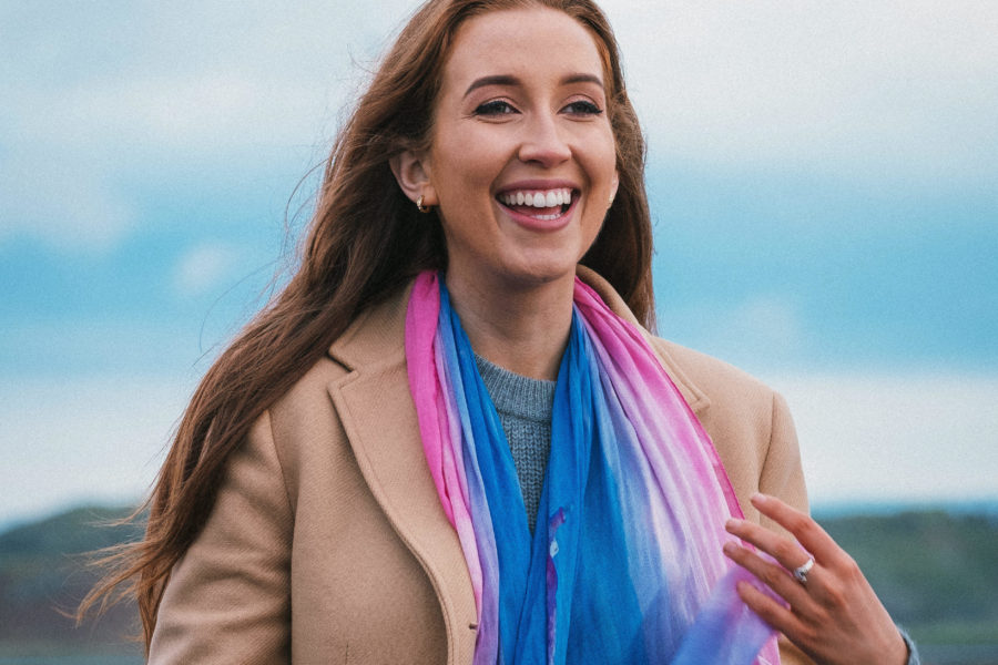 Happy young woman with long red hair wearing a pink and blue scarf