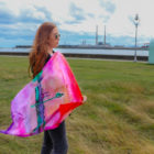 Young woman with long red hair holding a bright colourful silk scarf